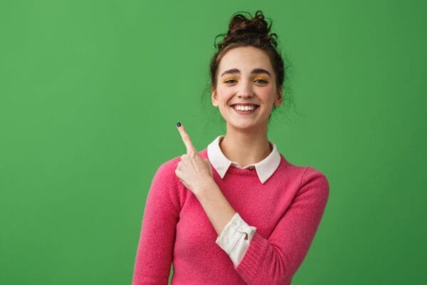 Image of a woman who is happy to learn Google Ads and landing page strategy: ad copy that hooks with landing pages that drive conversions. colourful image with vivid green background and smiling young woman with pink jumper.